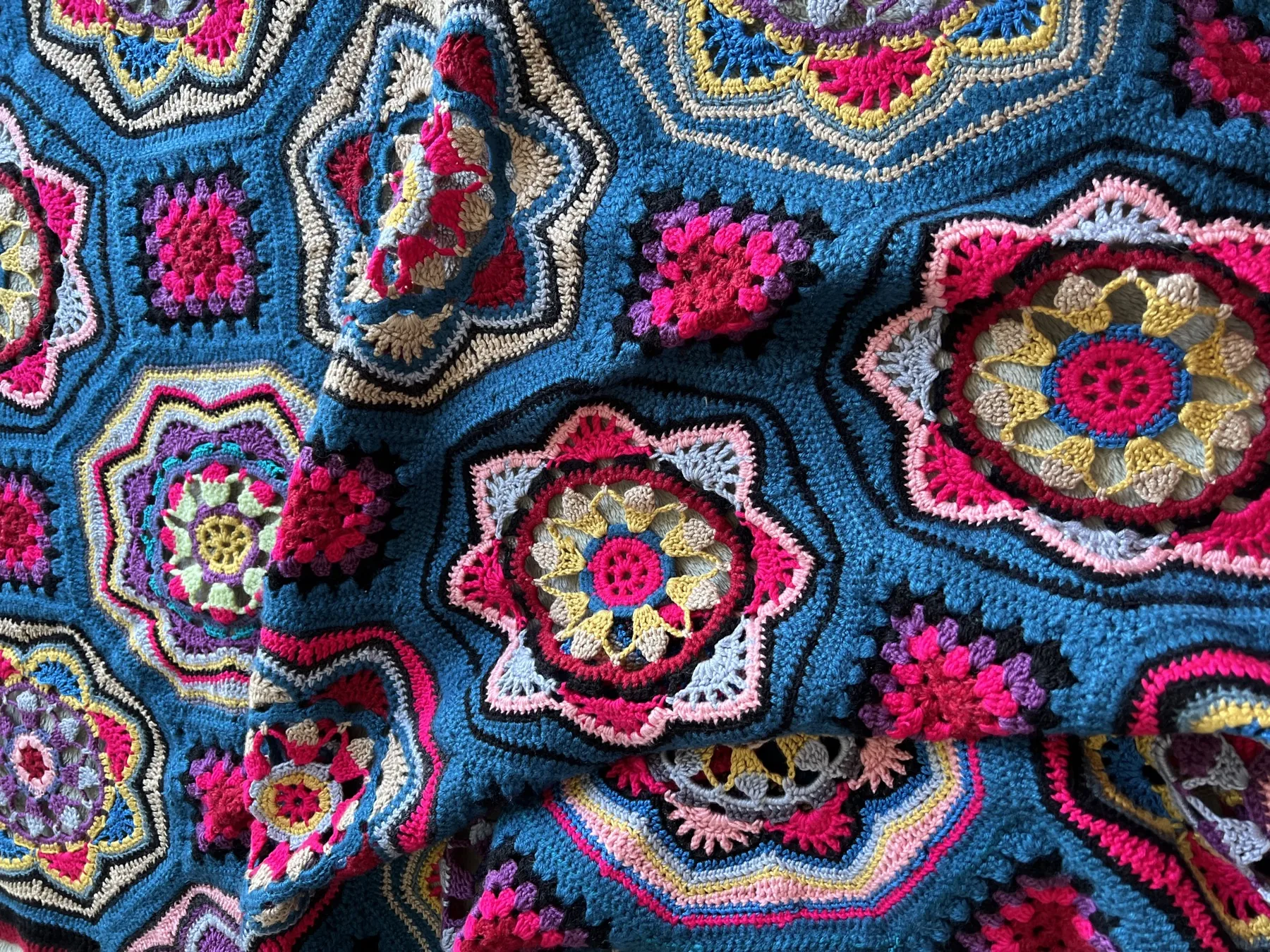 Hand-crocheted blanket in teal and jewel tones